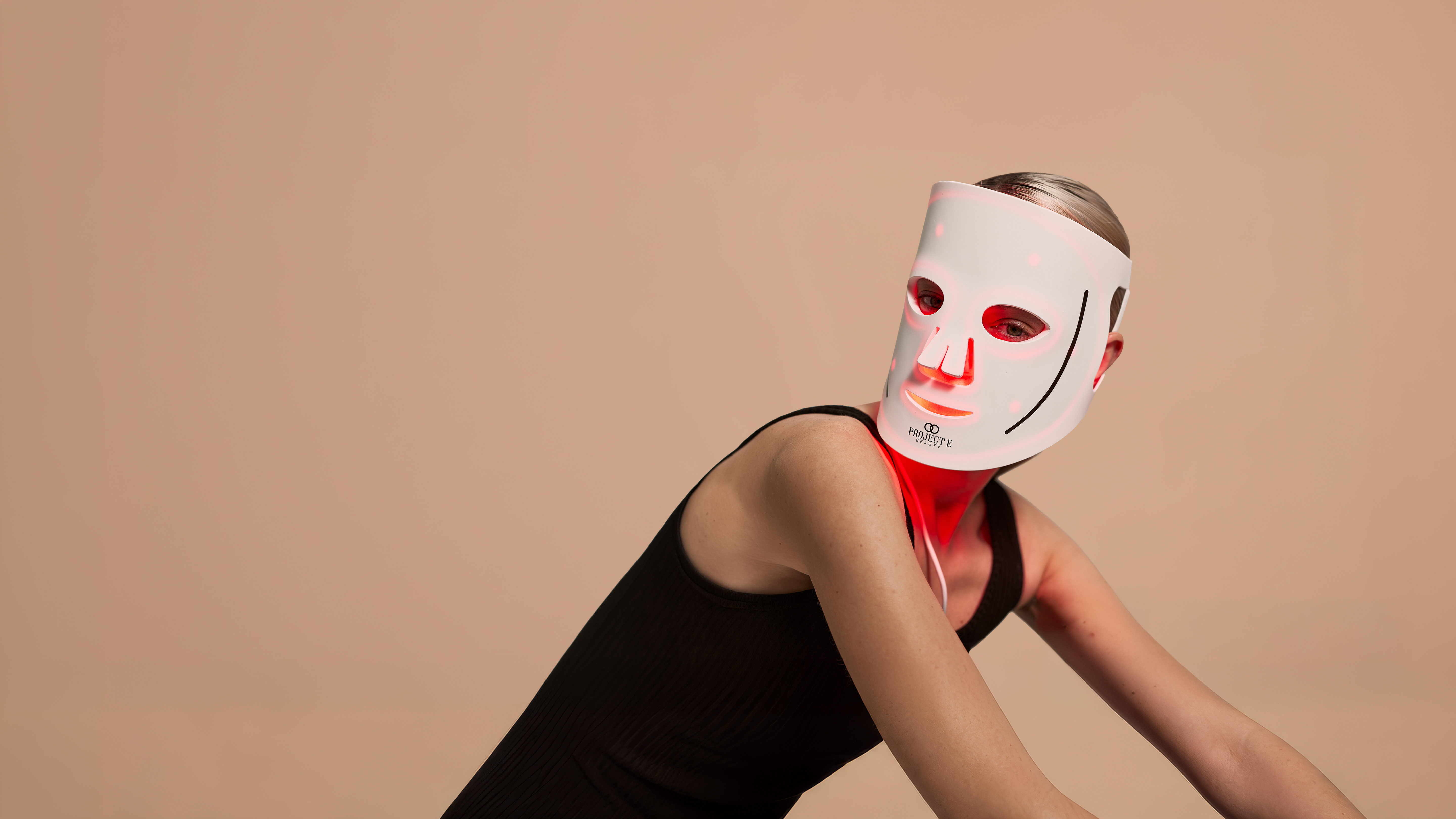 Project E Beauty LumaLux mask worn by a woman in stylized editorial pose.